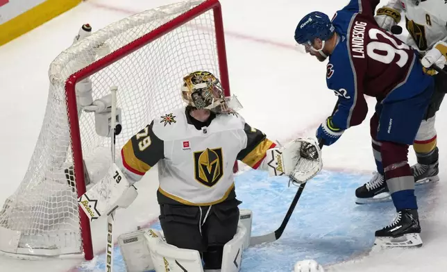 Colorado Avalanche left wing Gabriel Landeskog, right, tries to redirect the puck as Vegas Golden Knights goaltender Carter Hart defends during the first period in Game 1 of the Western Conference finals NHL hockey Stanley Cup playoff series Wednesday, May 20, 2026, in Denver. (AP Photo/David Zalubowski)