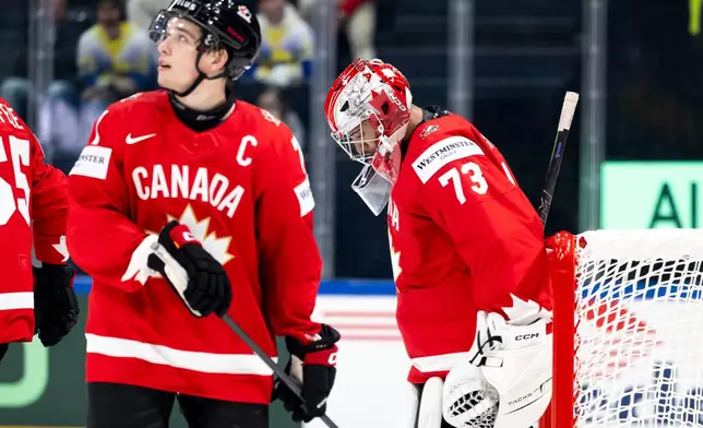 Canada's Macklin Celebrini, left, and goaltender Jet Greaves, right, react during a Group B preliminary round game between Canada and Sweden at the men's ice hockey world championship in Fribourg, Switzerland, Friday, May 15, 2026. (Anthony Anex/Keystone via AP)