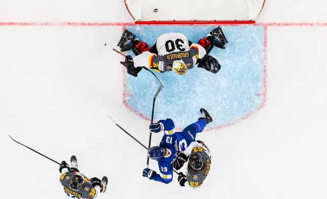 Germany's goaltender Philipp Grubauer, top, fails to save a goal by Finland's Anton Lundell, as Germany's Fabio Wagner, left, and Germany's Moritz Seider, right, vie with Finland's Jesse Puljujarvi, center, during the Group A preliminary round game between Finland and Germany at the men's ice hockey world championship in Zurich, Switzerland, Friday, May 15, 2026. (Michael Buholzer/Keystone via AP)