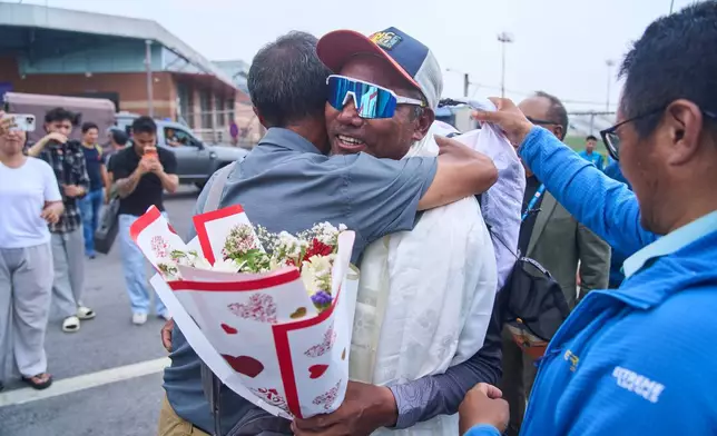 Renowned Sherpa mountain guide Kami Rita, center right, returning from Mount Everest after his record 32nd successful ascent is presented with shawls and flowers as he arrives at an airport in Kathmandu, Nepal, Friday, May 22, 2026. (AP Photo/Niranjan Shrestha)