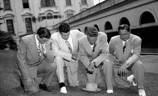 FILE - Evangelist Billy Graham, second from right, kneels with, from left, Jerry Beavan, Clifford Barrows and Grady Wilson, on the White House lawn in Washington, July 14, 1950, praying for President Truman in his handling of the Korean crisis. (AP Photo)