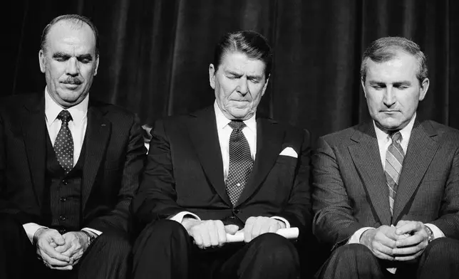 FILE - President Ronald Reagan prays with National Association of Evangelicals President Arthur Gay, left, following his address to the organization's convention asking for help in winning approval of a constitutional amendment permitting prayer in school in Columbus, Ohio, March 7, 1984. (AP Photo/Barry Thumma, File)