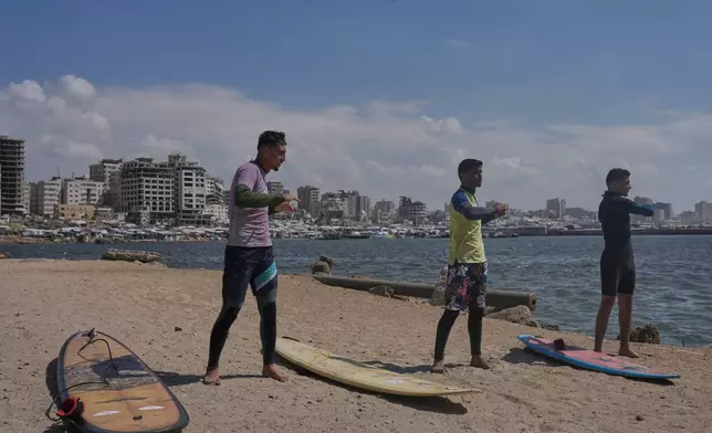 Palestinians Tahseen Abu Assi, left, Khalil Abu Jayyab, center, and Abed Rahim Alostaz warm up before surfing on the beach in Gaza City, Monday, May 4, 2026. (AP Photo/Jehad Alshrafi)