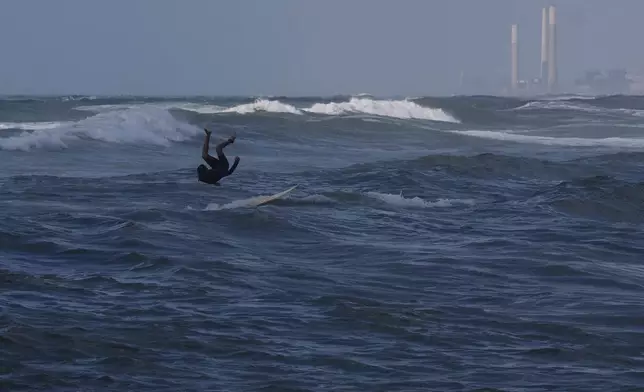 A Palestinian jumps into the waters of the Mediterranean Sea as he surfs on the beach in Gaza City, Monday, May 4, 2026. (AP Photo/Jehad Alshrafi)