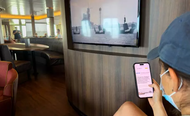 A passenger on the hantavirus-stricken cruise ship, MV Hondius, reads the news on his mobile phone during the voyage to Spain's port of Tenerife, May 6, 2026. (AP Photo)
