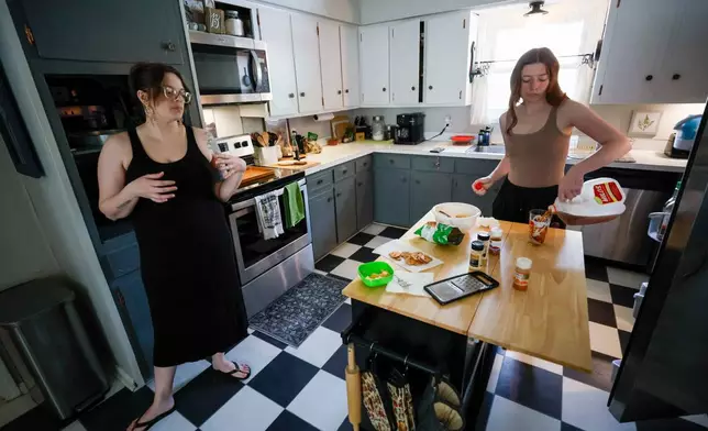 Emelia Pierce, 14, pours a glass of store-bought sweet tea while talking with her mother, Stormy Bost, in their kitchen in Calhoun, Ga., on March 29, 2026. (Miguel Martinez/Atlanta Journal-Constitution via AP)