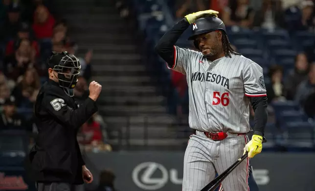 Minnesota Twins' Josh Bell (56) walks back to the dugout after striking out against Cleveland Guardians starting pitcher Tanner Bibee as umpire Paul Clemons, left, makes the call during the fourth inning of a baseball game, Saturday, May 9, 2026, in Cleveland. (AP Photo/Phil Long) CORRECTION