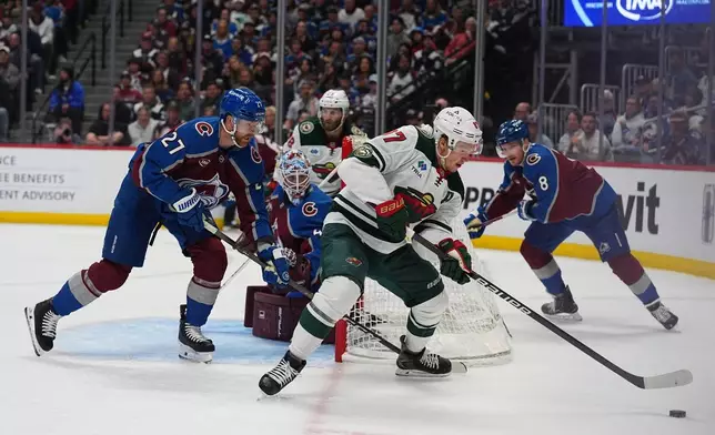 Minnesota Wild left wing Kirill Kaprizov, front right, collects the puck as Colorado Avalanche defensemen Brett Kulak, front left, and Cale Makar, back, cover in the second period of Game 1 of an NHL hockey Stanley Cup second-round playoff series Sunday, May 3, 2026, in Denver. (AP Photo/David Zalubowski)