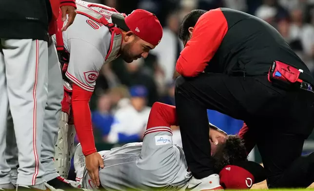 Cincinnati Reds relief pitcher Emilio Pagán, bottom, is checked by catcher Tyler Stephenson, left, and a team trainer after an injury during the ninth inning of a baseball game against the Chicago Cubs in Chicago, Tuesday, May 5, 2026. (AP Photo/Nam Y. Huh)