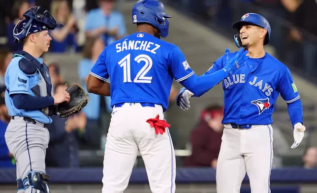 Toronto Blue Jays' Andres Gimenez, right, celebrates after his three-run home run with teammate Jesus Sanchez (12) during second-inning baseball game action against the Tampa Bay Rays in Toronto, Monday, May 11, 2026. (Frank Gunn/The Canadian Press via AP)