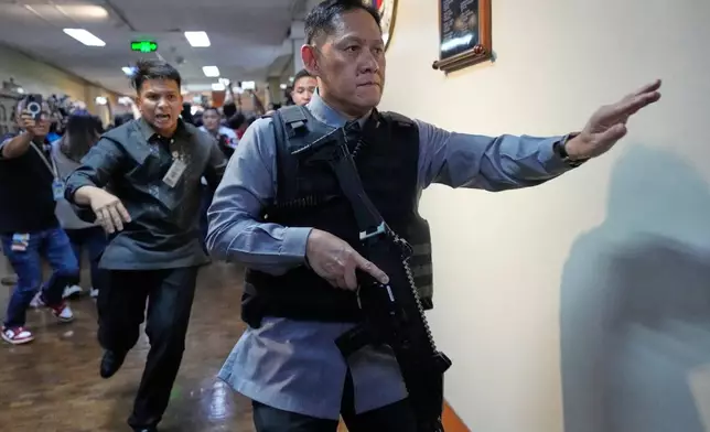 Senate security run after gunfire was heard along a hallway at the Philippine Senate in Pasay, Philippines, Wednesday, May 13, 2026. (AP Photo/Aaron Favila)