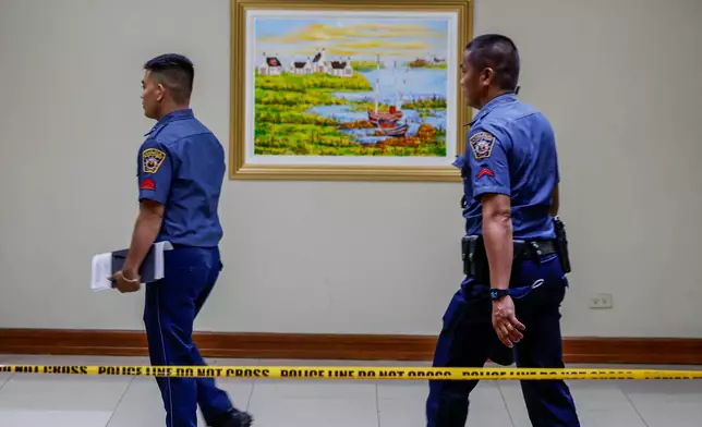 Police personnel walk behind a cordoned-off area inside the Philippine Senate premises in Pasay City Thursday, May 14, 2026, where gunshots were fired Wednesday in connection with a senator who was issued a warrant of arrest by the International Criminal Court. (AP Photo/Gerard Carreon)