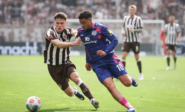 St. Pauli's Arkadiusz Pyrka, left, and Mainz's Nadiem Amiri battle for the ball during the German Bundesliga soccer match between FC St. Pauli and FSV Mainz 05 in Hamburg, Germany, Sunday, May 3, 2026. (Christian Charisius/dpa via AP)