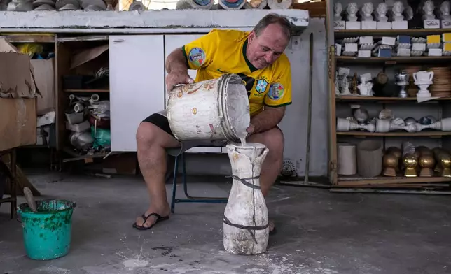Jarbas Meneghini Carlini demonstrates how he makes FIFA World Cup trophy replicas at his home in Rio de Janeiro, Friday, May 15, 2026. (AP Photo/Bruna Prado)