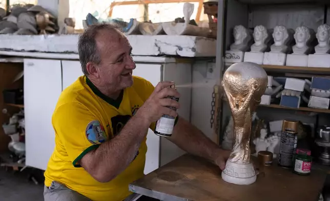Jarbas Meneghini Carlini sprays a FIFA World Cup trophy replica he made, at his home in Rio de Janeiro, Friday, May 15, 2026. (AP Photo/Bruna Prado)