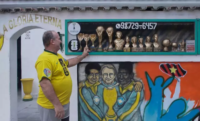 Jarbas Meneghini Carlini shows off FIFA World Cup trophy replicas he made, now decorations in front of his house, in Rio de Janeiro, Friday, May 15, 2026. (AP Photo/Bruna Prado)
