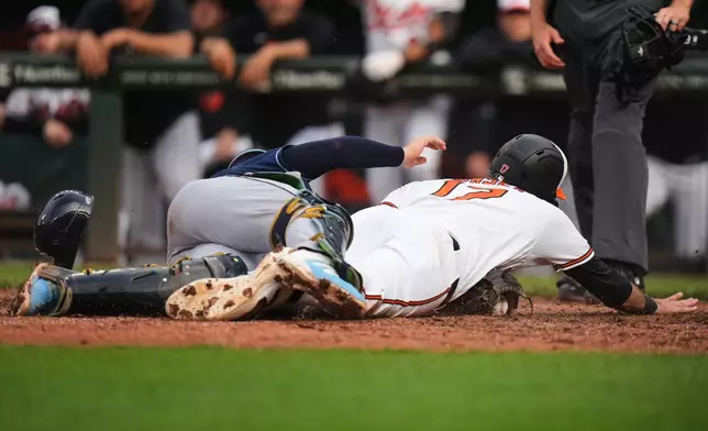 Baltimore Orioles' fielder Colton Cowser (17) scores against Tampa Bay Rays catcher Hunter Feduccia, left, during the 12th inning of a baseball game, Monday, May 25, 2026, in Baltimore. (AP Photo/Stephanie Scarbrough)