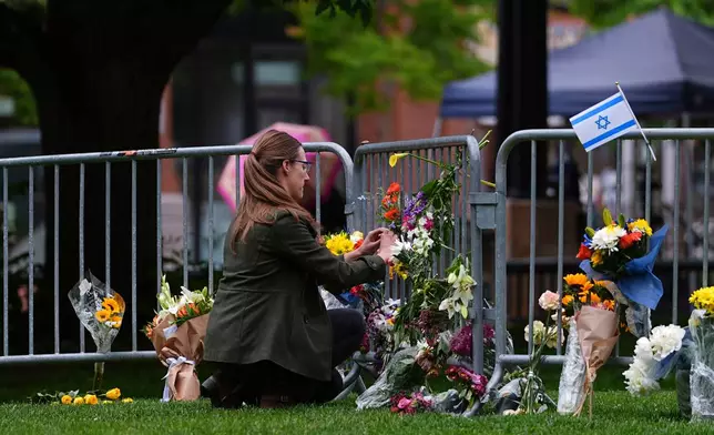 FILE - A woman places a bouquet of flowers at a makeshift memorial for victims of an attack outside of the Boulder County, Colo., courthouse Tuesday, June 3, 2025, in Boulder, Colo. (AP Photo/David Zalubowski, File)