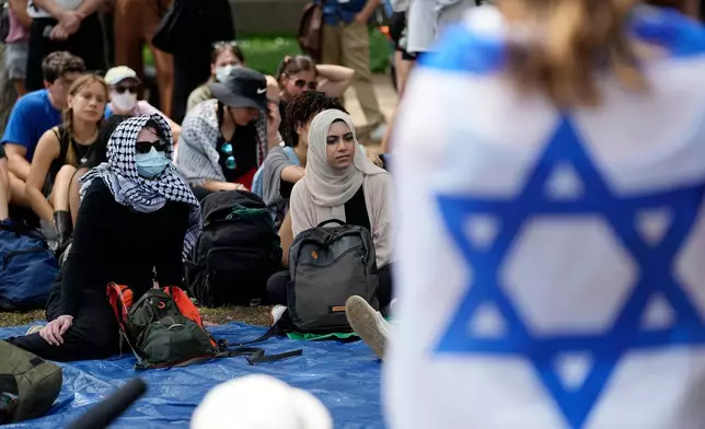 FILE - A student wrapped in an Israeli flag listens to Pro-Palestinian protesters gathered on campus at the University of Texas at Austin, on April 30, 2024, in Austin, Texas. (AP Photo/Eric Gay, File)