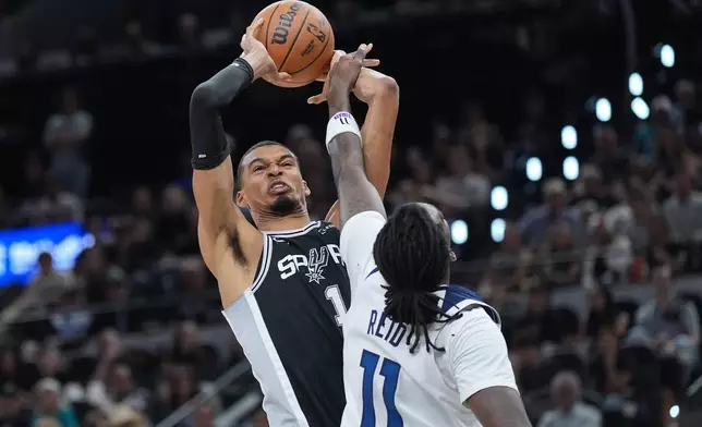 San Antonio Spurs forward Victor Wembanyama (1) grabs a rebound over Minnesota Timberwolves center Naz Reid (11) during the first half of Game 5 of an NBA basketball second-round playoffs series in Minneapolis, Tuesday, May 12, 2026. (AP Photo/Eric Gay)
