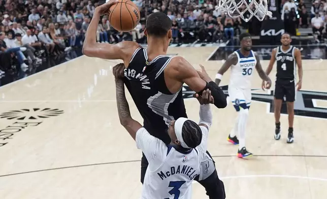 San Antonio Spurs forward Victor Wembanyama (1) pulls down a rebound over Minnesota Timberwolves forward Jaden McDaniels (3) during the first half of Game 5 of an NBA basketball second-round playoffs series in Minneapolis, Tuesday, May 12, 2026. (AP Photo/Eric Gay)