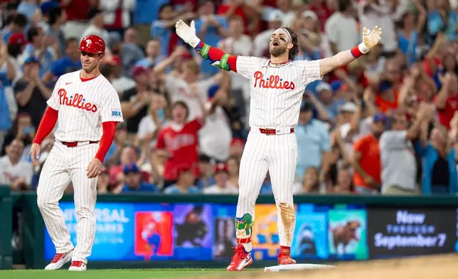 Philadelphia Phillies' Bryce Harper, right, reacts after his triple for the cycle during the fifth inning of a baseball game against the New York Mets, Saturday, June 20, 2026, in Philadelphia. (AP Photo/Chris Szagola)