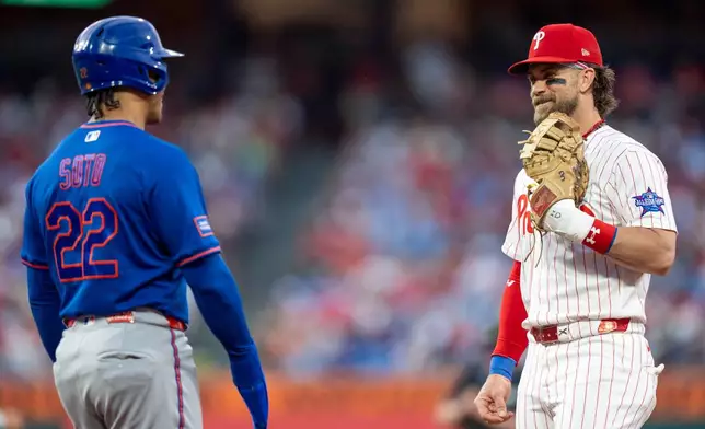 Philadelphia Phillies first baseman Bryce Harper, right, talks with New York Mets' Juan Soto, left, during the third inning of a baseball game, Saturday, June 20, 2026, in Philadelphia. (AP Photo/Chris Szagola)