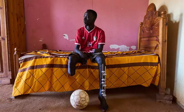 Omer al-Toum, 33, who lost his leg and arm by the explosion of unexploded ordnance, sits in his bedroom in Bahri, on the outskirts of Khartoum, Thursday, April 23, 2026. (AP Photo/Bernat Armangue)
