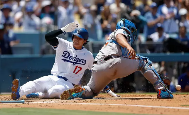 Los Angeles Dodgers designated hitter Shohei Ohtani (17) slides into home plate to score on a single hit by Los Angeles Dodgers' Max Muncy as Baltimore Orioles catcher Samuel Basallo readies to catch the ball during the first inning of a baseball game, Sunday, June 21, 2026, in Los Angeles. (AP Photo/Caroline Brehman)