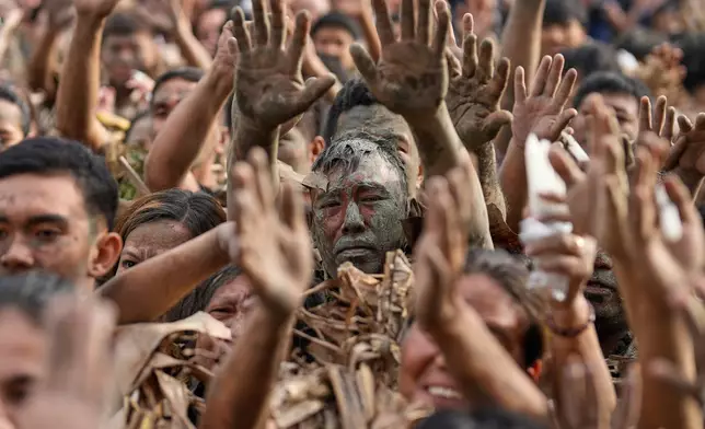 Melencio Neuda, center, and other devotees who participated in the mud people festival raise their hands during a mass on the feast day of Saint John the Baptist at Bibiclat, Nueva Ecija province, northern Philippines, Wednesday, June 24, 2026. (AP Photo/Aaron Favila)