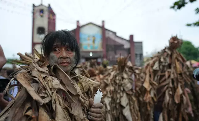 A Catholic devotee covered in mud and dried banana leaves participate in the mud people festival on the feast day of Saint John the Baptist at Bibiclat, Nueva Ecija province, northern Philippines on Wednesday, June 24, 2026. (AP Photo/Aaron Favila)