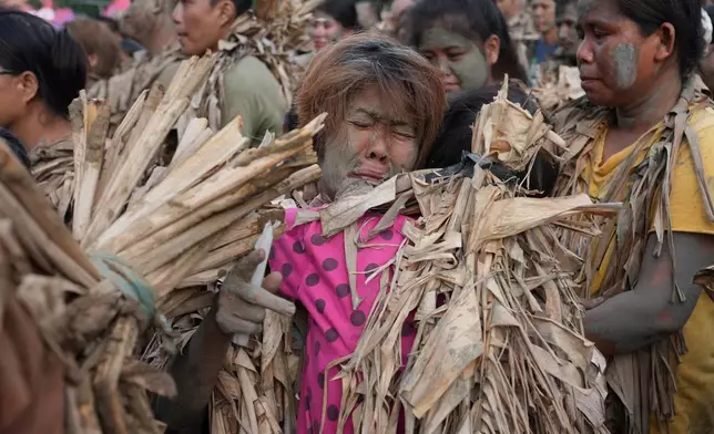 Catholic devotee covered in mud and dried banana leaves reacts as they participate at the mud people festival on the feast day of Saint John the Baptist at Bibiclat, Nueva Ecija province, northern Philippines on Wednesday, June 24, 2026. (AP Photo/Aaron Favila)