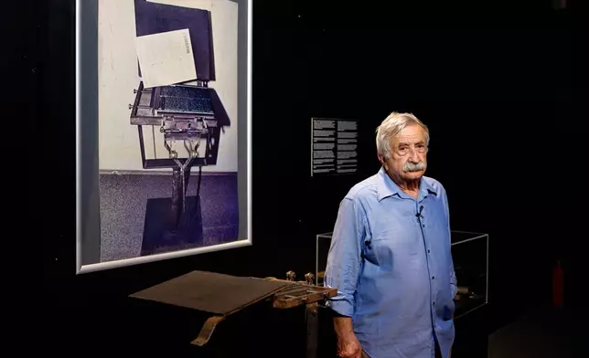 Journalist Petre Mihai Bacanu stands next to a clandestine printing press, belonging to him that was confiscated by the secret police in early 1989, during the opening of the "A.REST 1989 — The Securitate Video Archive" exhibition, at the National History Museum of Romania, in Bucharest, Romania, Tuesday, June 16, 2026. (AP Photo/Andreea Alexandru)