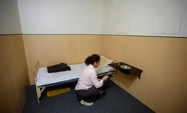 Oana Demetriade, historian at the National Council for Studying the Securitate Archives (CNSAS), puts the final touches in a replica of a Securitate prison cell, a day before the opening of the "A.REST 1989 — The Securitate Video Archive" exhibition, at the National History Museum of Romania, in Bucharest, Romania, Monday, June 15, 2026. (AP Photo/Andreea Alexandru)