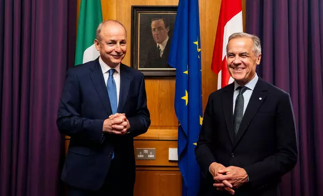 Prime Minister Mark Carney, right, poses for a photograph with Micheal Martin, Ireland's head of government, in front of a portrait of Harry Boland, at the Government Buildings in Dublin, on Saturday, June 13, 2026. (Christopher Katsarov /The Canadian Press via AP)