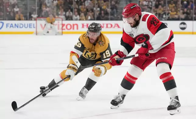 Vegas Golden Knights right wing Reilly Smith (19) reaches for the puck next to Carolina Hurricanes defenseman Sean Walker (26) during the second period in Game 6 of the NHL hockey Stanley Cup Final series, Sunday, June 14, 2026, in Las Vegas. (AP Photo/John Locher)