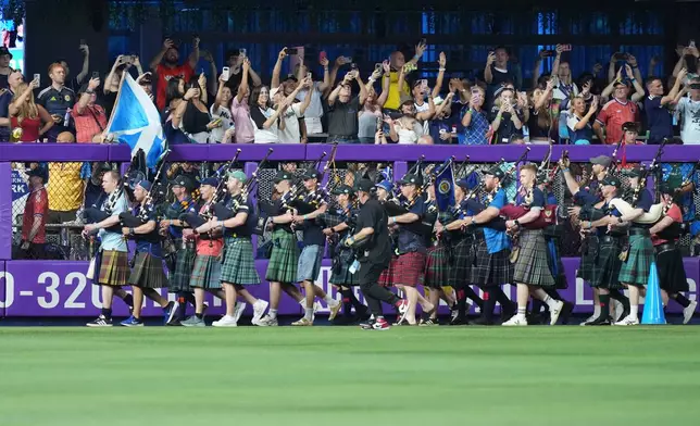 A bagpipe band marches in the outfield as Scotland soccer fans with the Tartan Army attend a baseball game between the Miami Marlins and the Texas Rangers, Monday, June 22, 2026, in Miami. (AP Photo/Lynne Sladky)