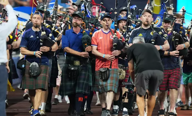 A bagpipe band marches in the outfield as Scotland soccer fans with the Tartan Army attend a baseball game between the Miami Marlins and the Texas Rangers, Monday, June 22, 2026, in Miami. (AP Photo/Lynne Sladky)