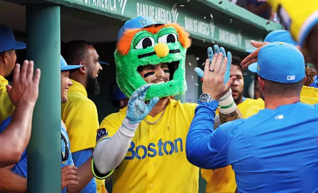 Boston Red Sox's Jarren Duran, center, wears a Wally the Green Monster head as he is congratulated in the dugout after his eighth-inning two-run home run during a baseball game against the Texas Rangers, Saturday, June 13, 2026, in Boston. (AP Photo/Jim Davis)