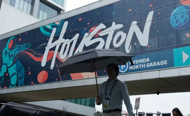 A convention attendee walk through the rain outside the George R. Brown Convention Center, Wednesday, June 17, 2026, in Houston. (AP Photo/Kevin M. Cox)