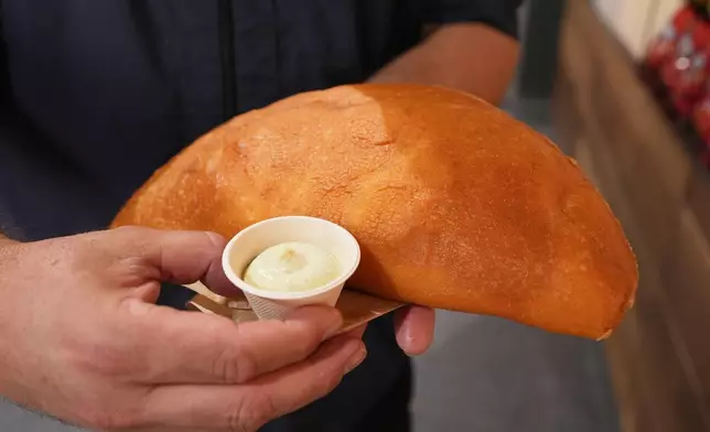 Lazaro Luya, the concession chef at Sol Cubano, displays their special, empanada mundial at Miami Stadium Sunday, June 21, 2026, in Miami Gardens, Fla. (AP Photo/Marta Lavandier)