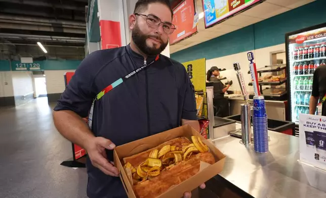 Lazaro Luya, the concession chef at Sol Cubano, displays their special, pan with lechon and fresh mariquitas at Miami Stadium Sunday, June 21, 2026, in Miami Gardens, Fla. (AP Photo/Marta Lavandier)