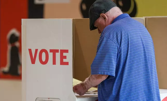 A voter looks over a ballot at a polling location inside the Shoppes at Northpark mall, Tuesday, June 16, 2026, in Oklahoma City. (AP Photo/Nate Billings)