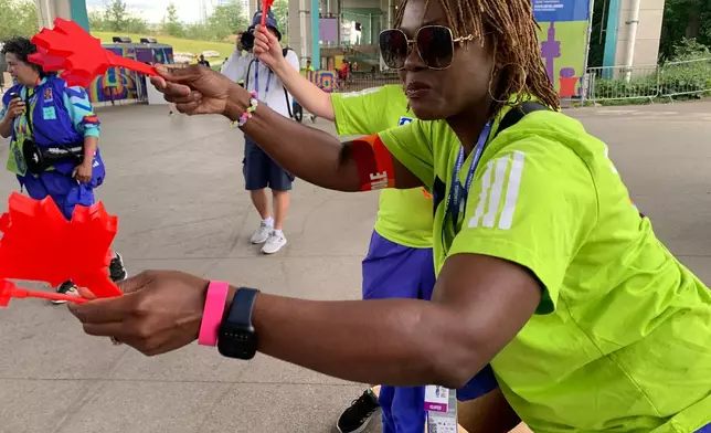 Volunteer Mbalu Lumor hands out "Canadian clappers" to attendees at the FIFA Fan Festival Wednesday, June 24, 2026, in Toronto. (AP Photo/Mike Householder)