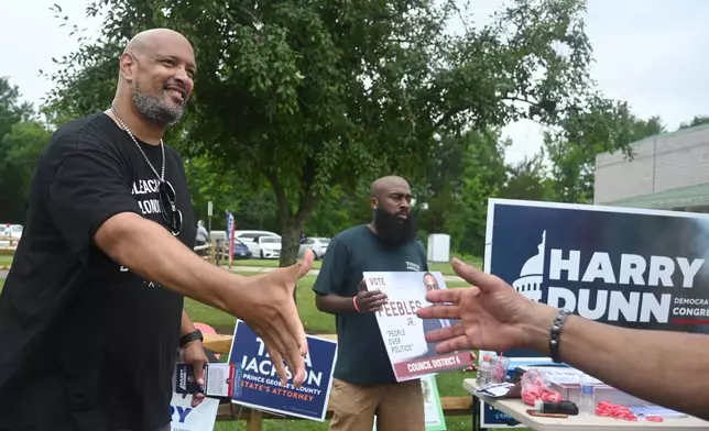 Harry Dunn, former U.S. Capitol police officer and candidate for U.S. Congress greets a voter Tuesday, June 23, 2026, in Upper Marlboro, Md. (AP Photo/Gail Burton)