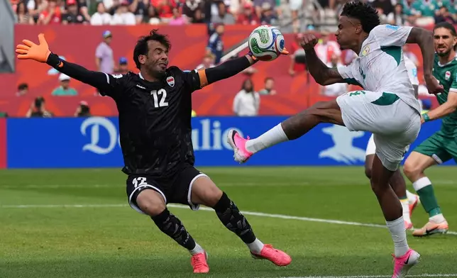 Senegal's Ismail Jakobs, right, kicks the ball past Iraq goalkeeper Jalal Hassan (12) during the World Cup Group I soccer match between Senegal and Iraq in Toronto, Friday, June 26, 2026. (AP Photo/Stephanie Scarbrough)