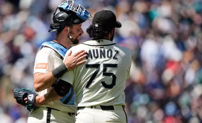 Seattle Mariners catcher Cal Raleigh greets relief pitcher Andrés Muñoz as they celebrate a win over the Boston Red Sox in a baseball game, Sunday, June 21, 2026, in Seattle. (AP Photo/Lindsey Wasson)
