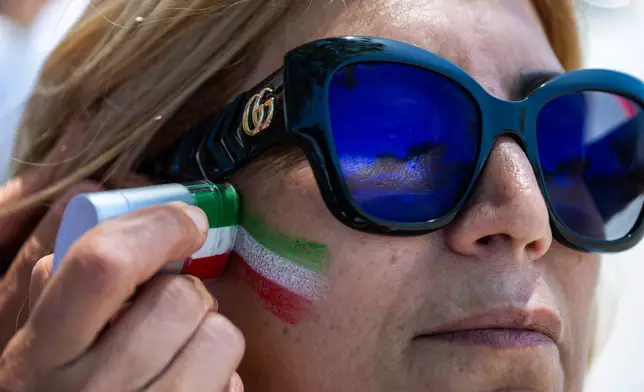A woman has her face painted during a protest in reaction to FIFA's ban of Iran's pre-revolutionary flag inside World Cup stadiums Sunday, June 7, 2026, in Inglewood, Calif. (AP Photo/Benjamin Hanson)