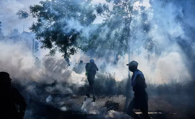 Protesters and others disperse amidst tear gas during a "No G7" demonstration in Geneva, Switzerland, Sunday, June 14, 2026, ahead of the G7 summit scheduled to take place June 15-17. (AP Photo/Laurent Cipriani)