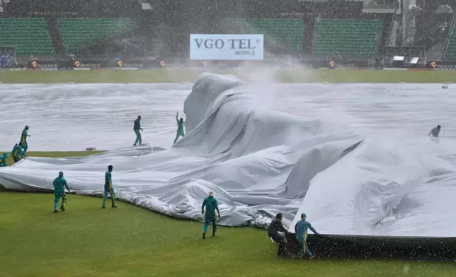Ground staff cover pitch and surrounding area during heavy rain at the Gaddafi Stadium before start of the third one-day international cricket match between Pakistan and Australia, in Lahore, Pakistan, Thursday, June 4, 2026. (AP Photo/K.M. Chaudary)